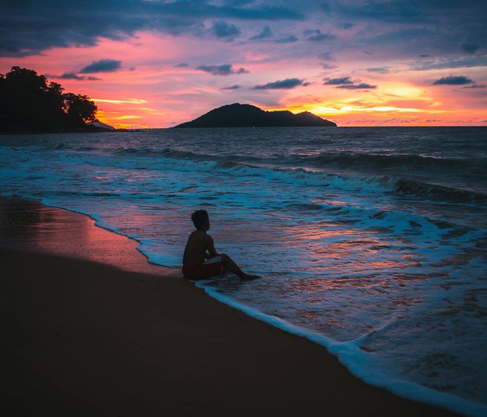 Silhouette of a person stretching against a vibrant sunrise.